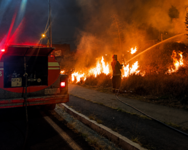 Bombero combate un incendio de vegetación durante una emergencia nocturna en Ibarra
