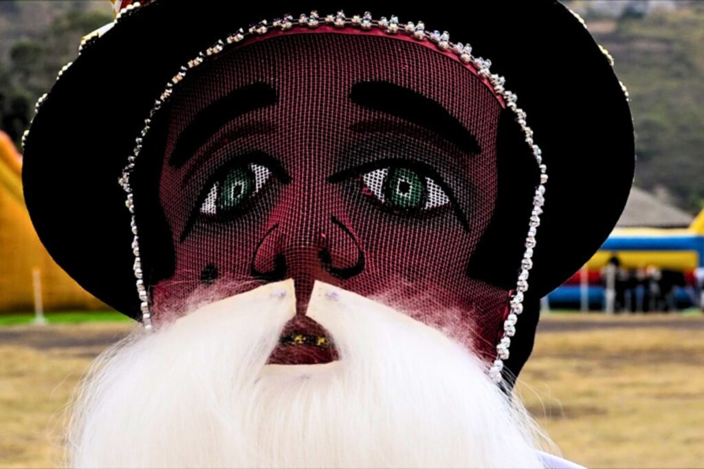 Las coloridas caretas de ojos claros y los pañolones distinguen a los sanjuaneros durante la celebración tradicional de Yahuarcocha.