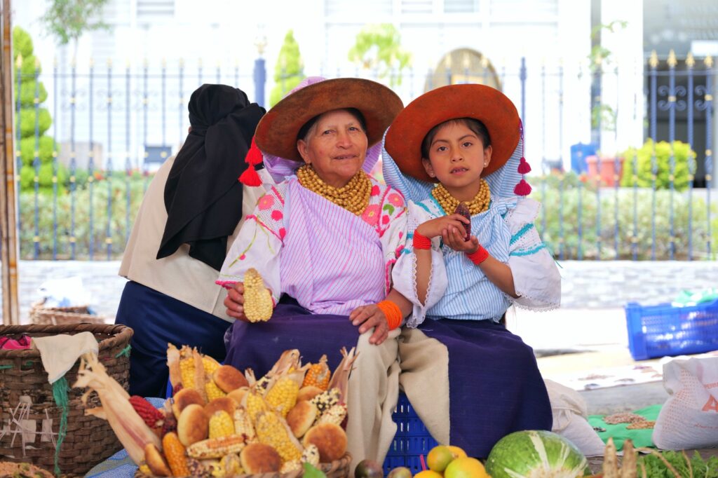Mujer y niña exhiben maíz y semillas nativas durante el Muyu Raymi en Cotacachi.