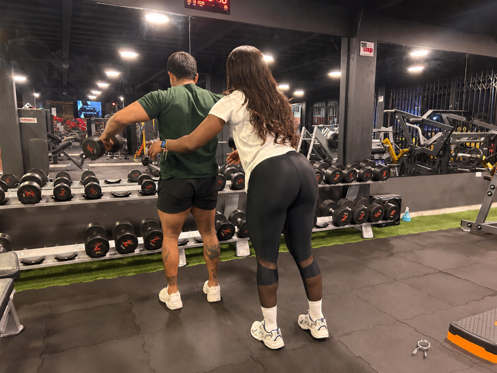 Entrenadora guía ejercicio con mancuernas en gimnasio de Ibarra