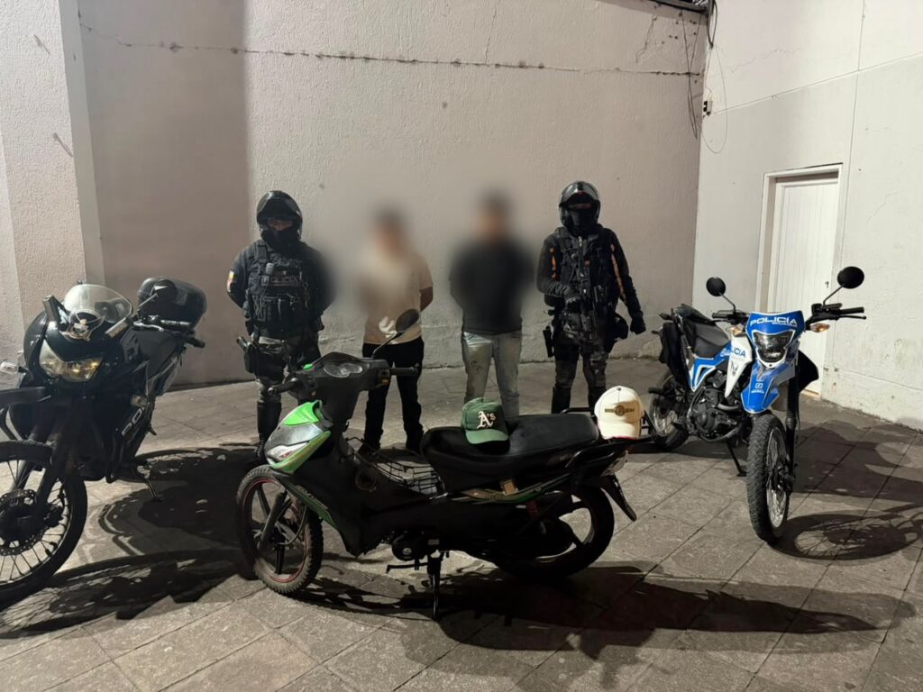 Dos ciudadanos aprehendidos por presunto robo de motocicleta en Ibarra junto a agentes de la Policía Nacional y el vehículo recuperado.