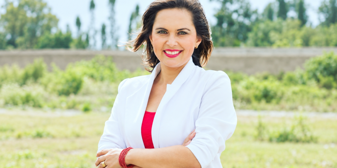 Andrea Cazar Villacís, aspirante imbabureña al cargo de Fiscal General del Estado, posa frente a un paisaje verde.