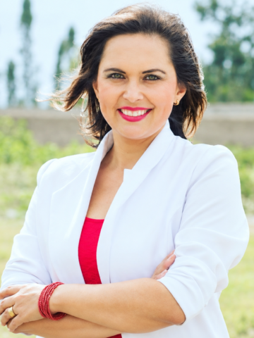 Andrea Cazar Villacís, aspirante imbabureña al cargo de Fiscal General del Estado, posa frente a un paisaje verde.