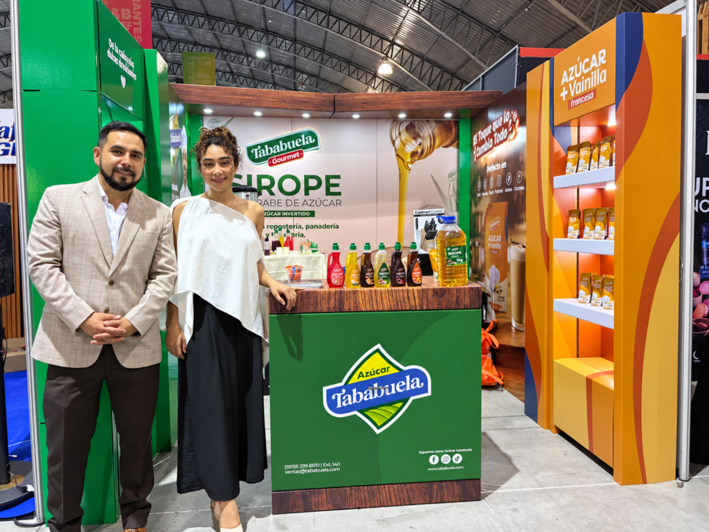 Dos personas junto al exhibidor de Tababuela Gourmet, con siropes y productos de Azúcar Tababuela en Expo HORECA 2026.