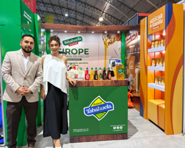 Dos personas junto al exhibidor de Tababuela Gourmet, con siropes y productos de Azúcar Tababuela en Expo HORECA 2026.