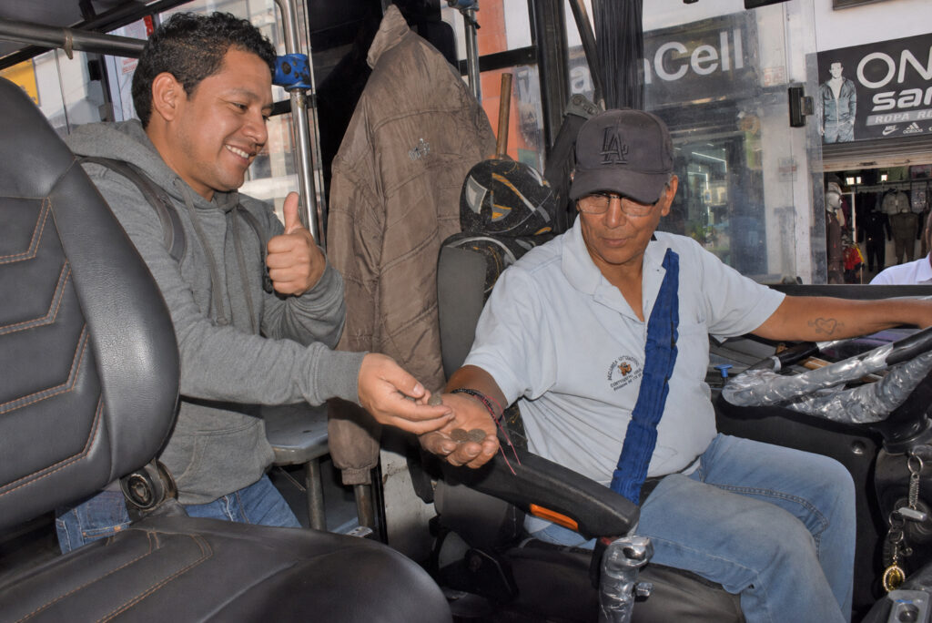 Un pasajero entrega monedas al conductor de un bus urbano de Ibarra.
