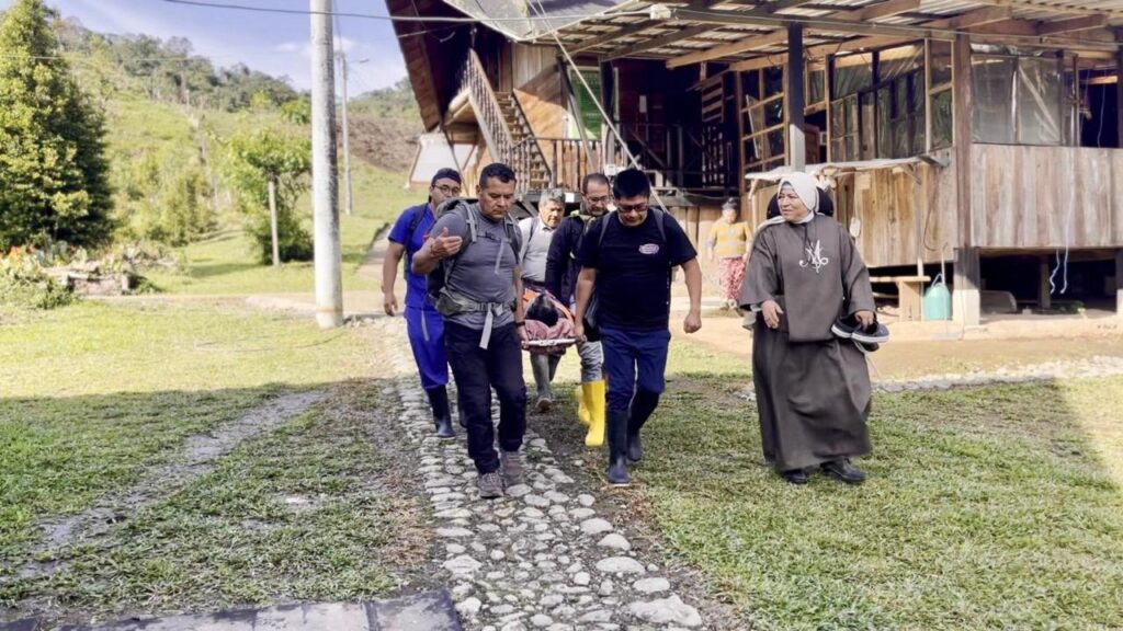 Integrantes de una brigada trasladan a un paciente en camilla junto a una religiosa en San Francisco de Palmira, sector de Lita.