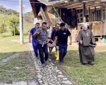 Integrantes de una brigada trasladan a un paciente en camilla junto a una religiosa en San Francisco de Palmira, sector de Lita.