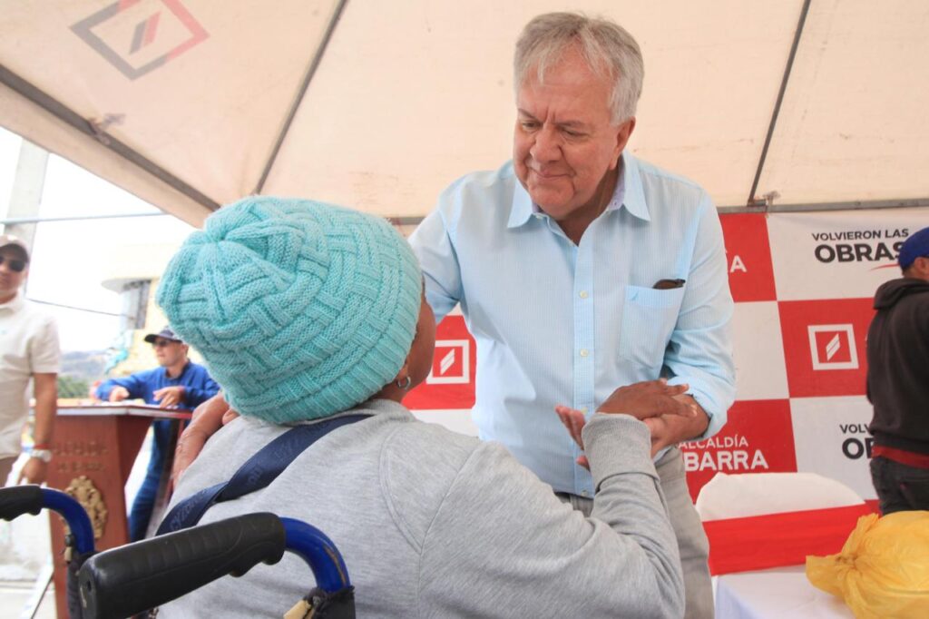 Álvaro Castillo, alcalde de Ibarra, saluda a una mujer que utiliza silla de ruedas durante una actividad municipal.