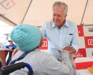 Álvaro Castillo, alcalde de Ibarra, saluda a una mujer que utiliza silla de ruedas durante una actividad municipal.